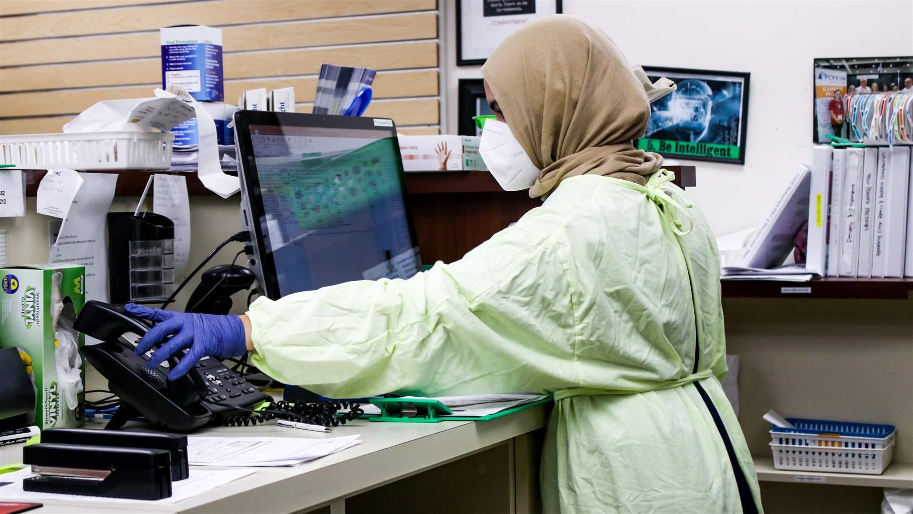 A lab technician hanging up their phone at their workstation. 