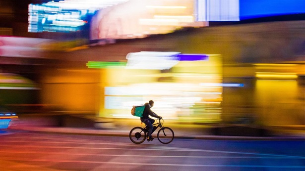 Blurred cityscape of a delivery driver on a bike riding down the road