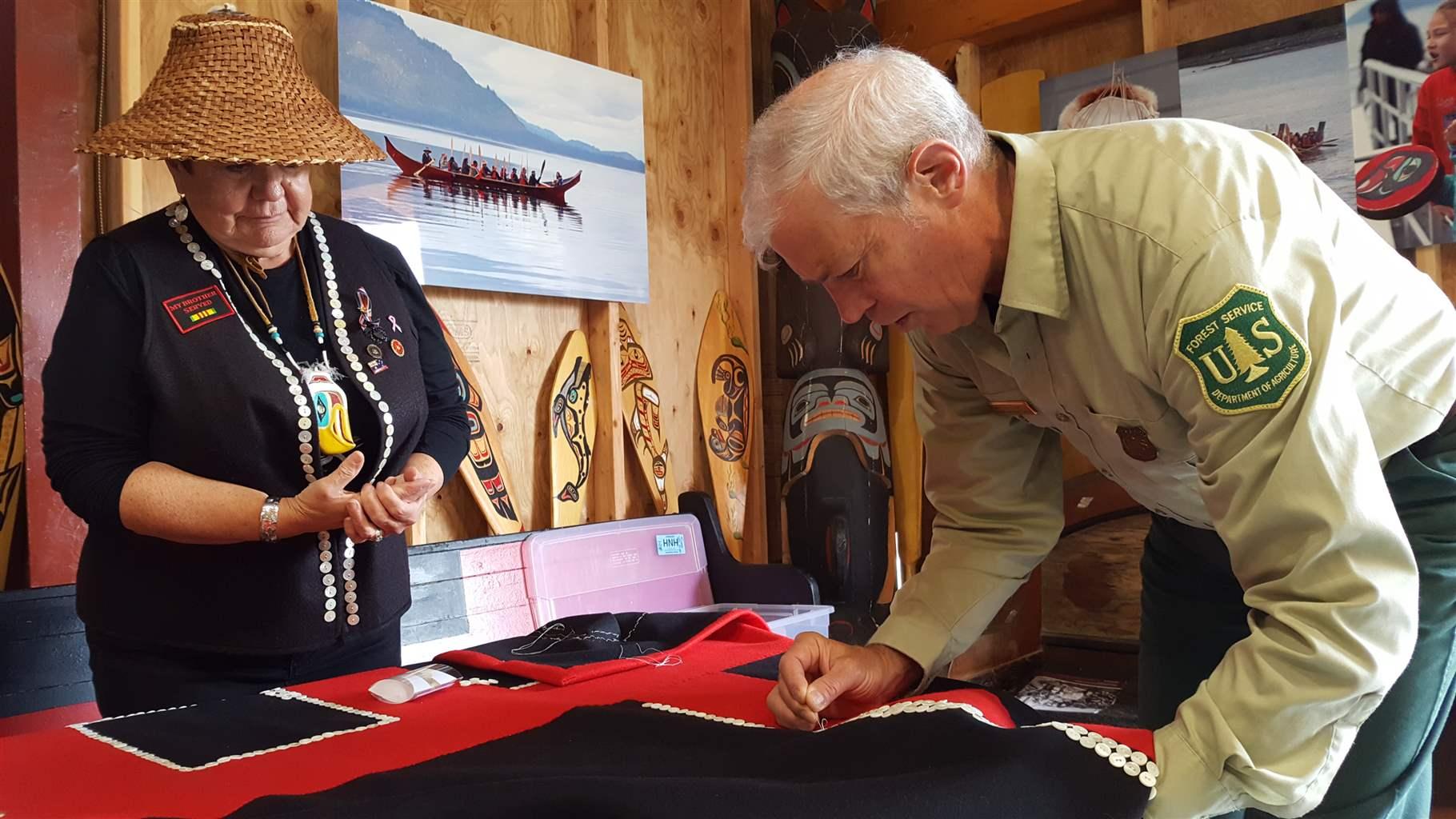 Charles Streuli sews a button onto a Tlingit blanket made to represent the healing process between the tribes.