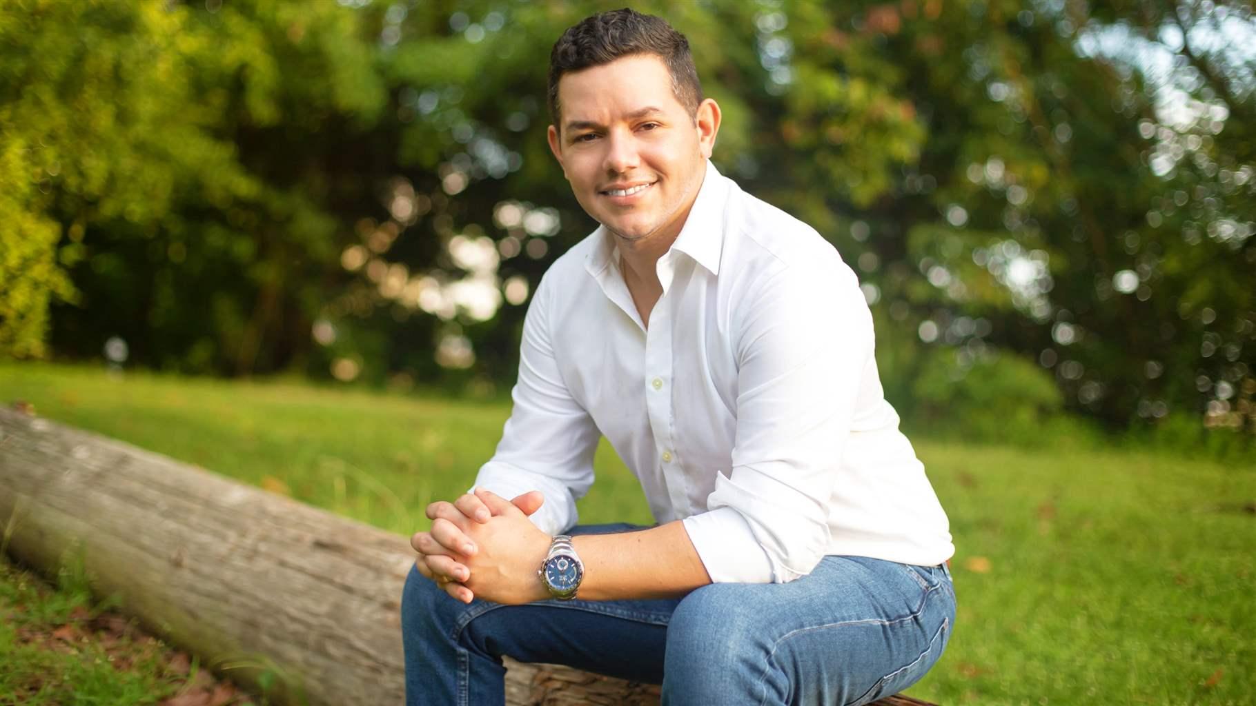 Alberto Mercado sitting on a log in the woods