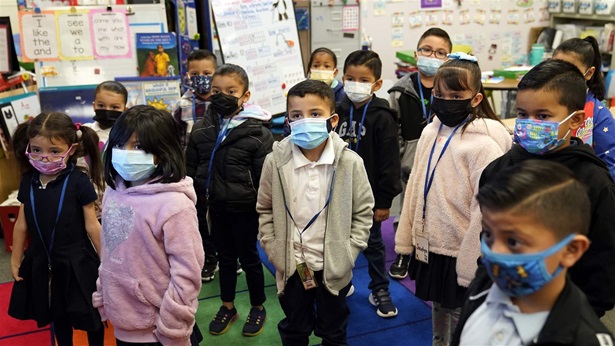 Kindergarteners wear masks while listening to their teacher amid the COVID-19 pandemic at Washington Elementary School Wednesday, Jan. 12, 2022, in Lynwood, Calif. California is making it easier for school districts to hire teachers and other employees amid staffing shortages brought on by the latest surge in coronavirus cases.