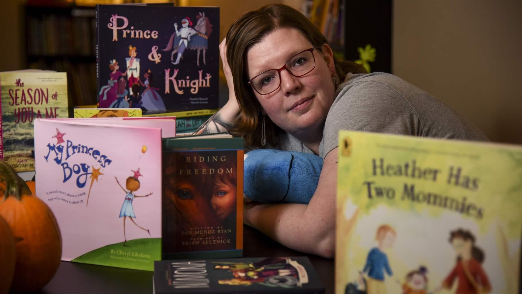 Charlotte McConnell sitting at a table filled with diverse children's books.