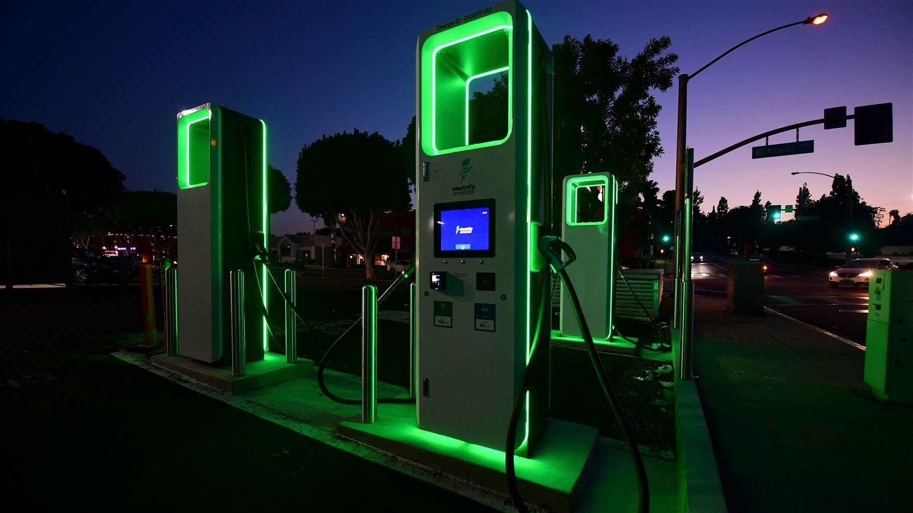 An EV charging station illuminated with green led light at night.
