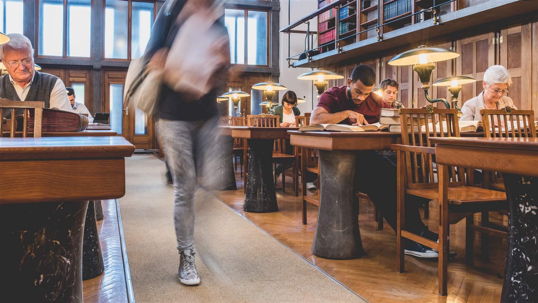 Students and seniors sitting and studying in a public library.