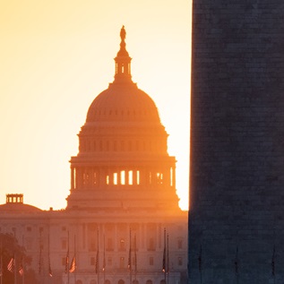A silhouette of the U.S. capitol building with the sun setting behind. 