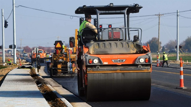 Worker on roller smoothing asphalt 