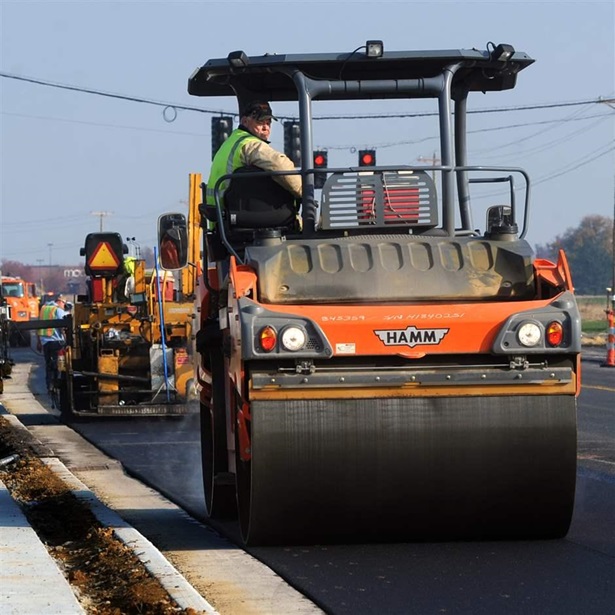 Worker on roller smoothing asphalt 