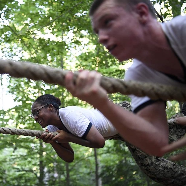 U.S. Naval Academy recruits climb along a rope on an obstacle course. 