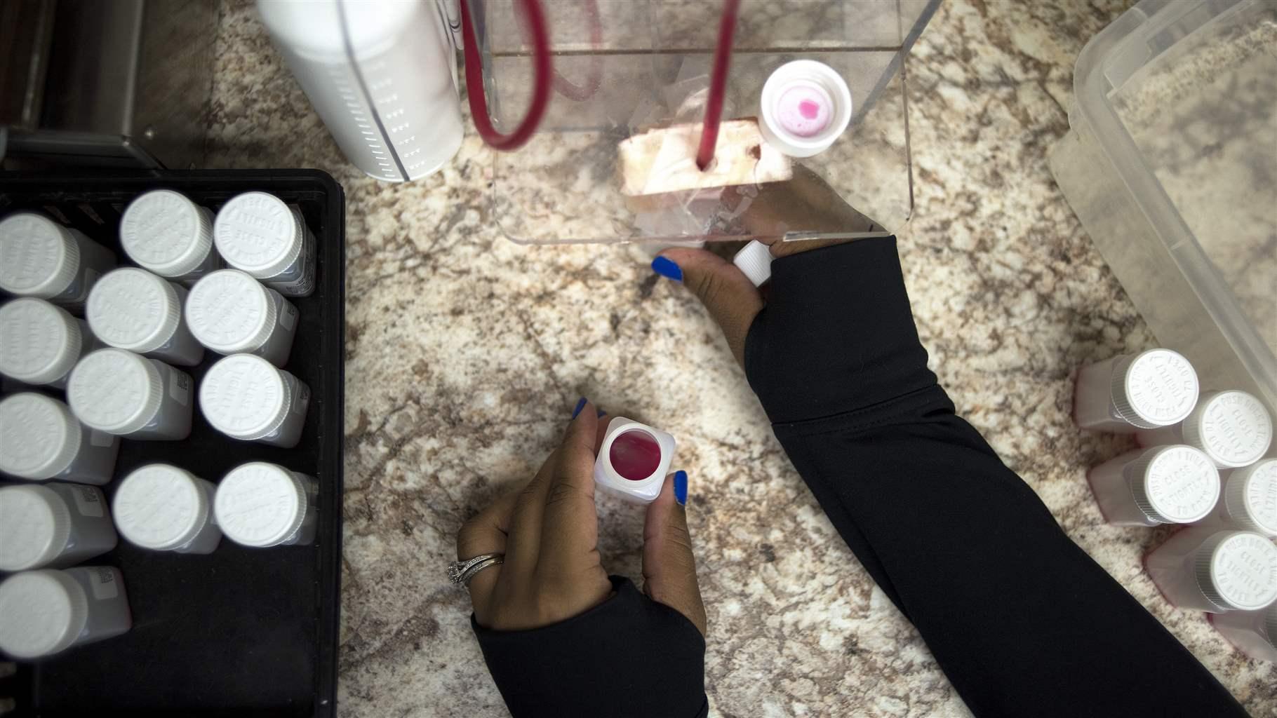 A nurse fills bottles with small amounts of liquid methadone for take-home prescriptions at a clinic in the Community Health Center in Akron, Ohio, Dec. 18, 2017. 