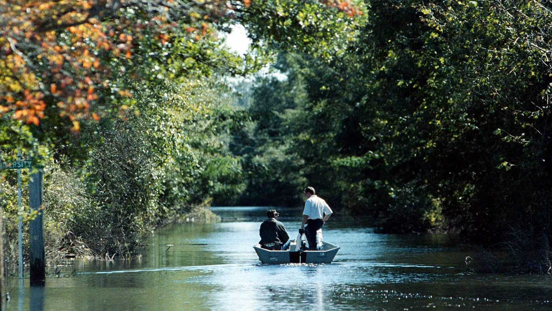 Mike Spencer, standing, a fireman with the Kinston Fire Dept., gives the Rev. Robert Campbell a ride down flooded Davis Street in Kinston, N.C., Thursday, Sept. 30, 1999. 