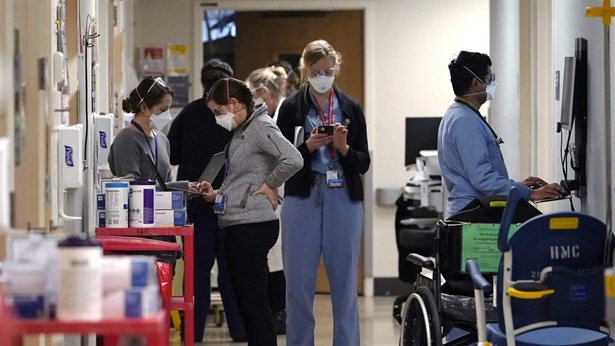 Medical workers fill a hallway in the acute care unit, where about half the patients are COVID-19 positive or in quarantine after exposure, of Harborview Medical Center, Friday, Jan. 14, 2022, in Seattle. Washington