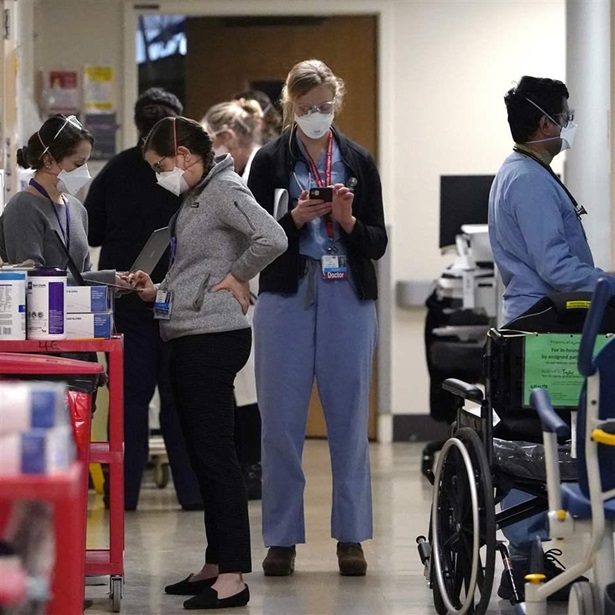 Medical workers fill a hallway in the acute care unit, where about half the patients are COVID-19 positive or in quarantine after exposure, of Harborview Medical Center, Friday, Jan. 14, 2022, in Seattle. Washington
