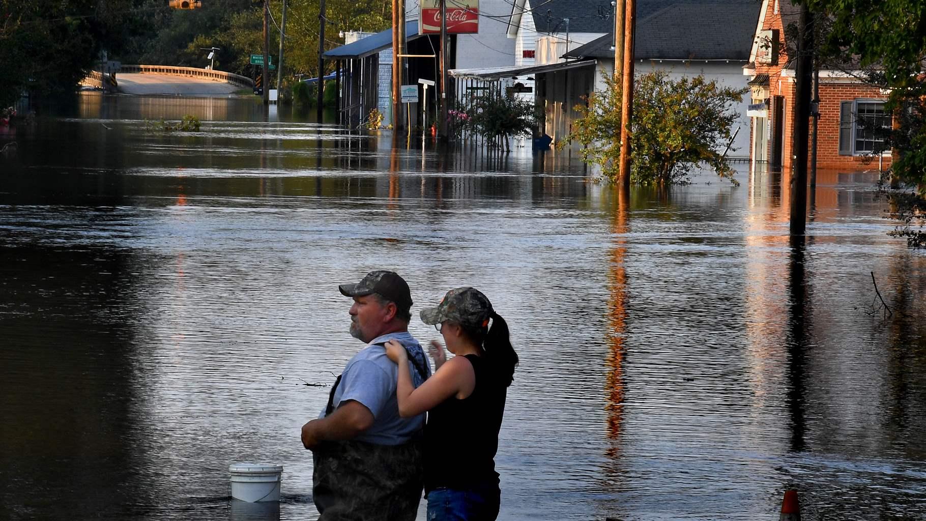 A father and daughter standing in a flooded street.