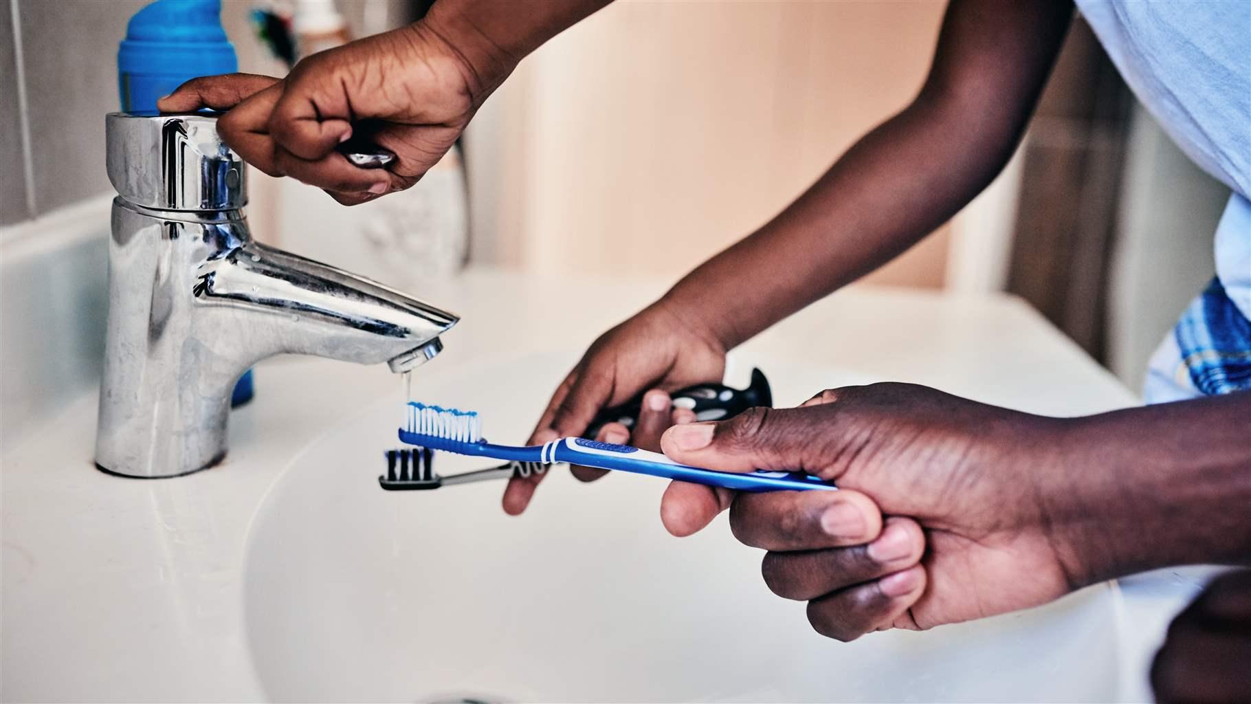 Man and son rinsing toothbrushes Man and son rinsing toothbrushes