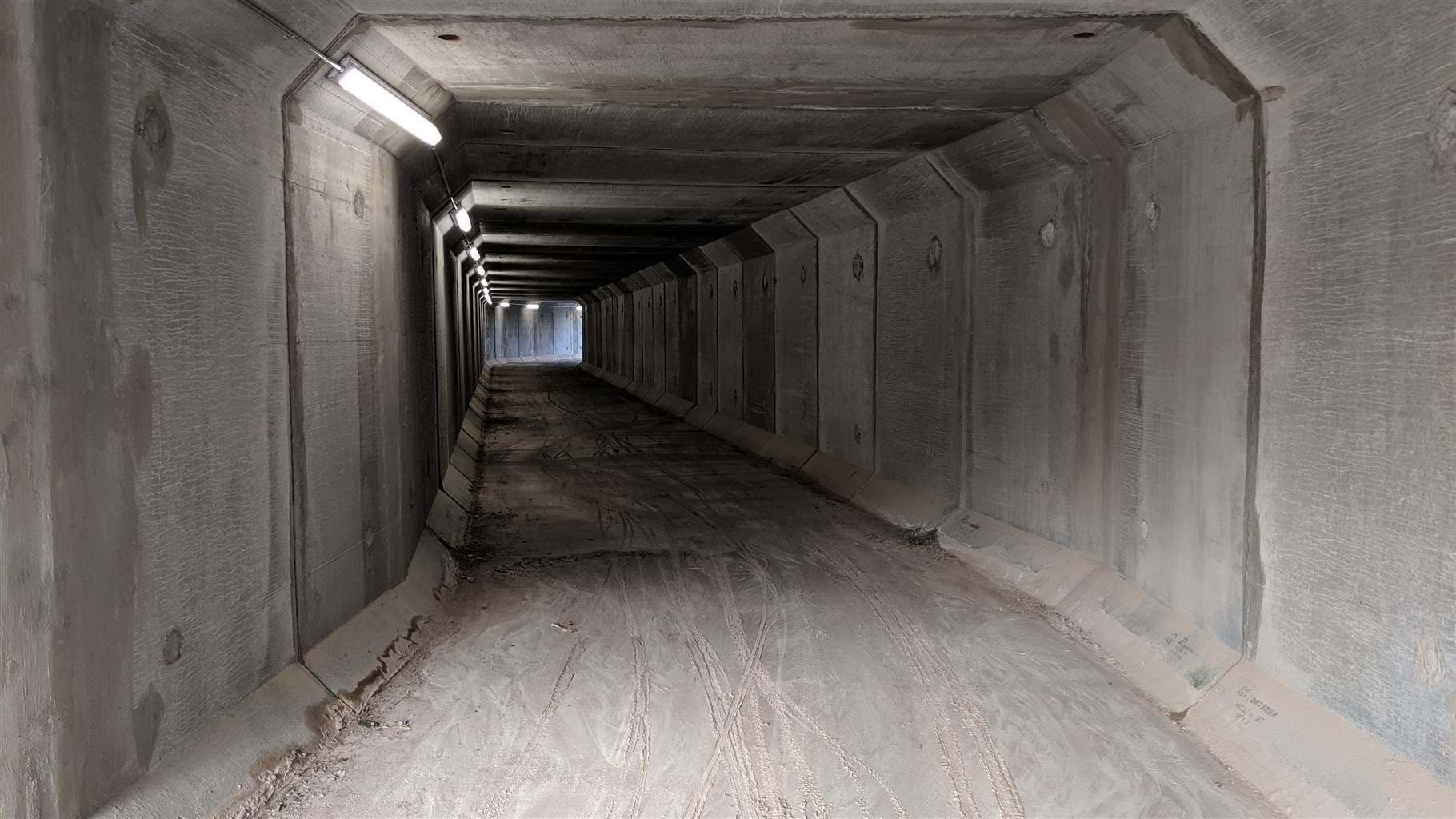 A concrete tunnel with lights along the left hand side. 
