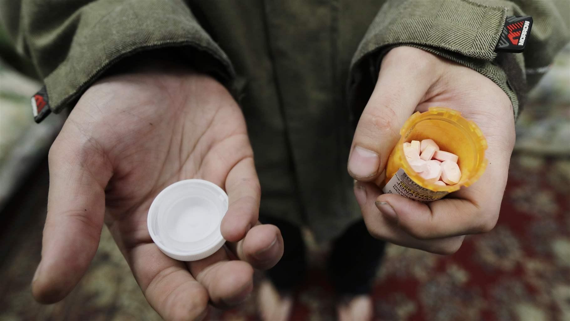 In this Nov. 14, 2019, photo, Jon Combes holds his bottle of buprenorphine, a medicine that prevents withdrawal sickness in people trying to stop using opiates, as he prepares to take a dose in a clinic in Olympia, Wash. 