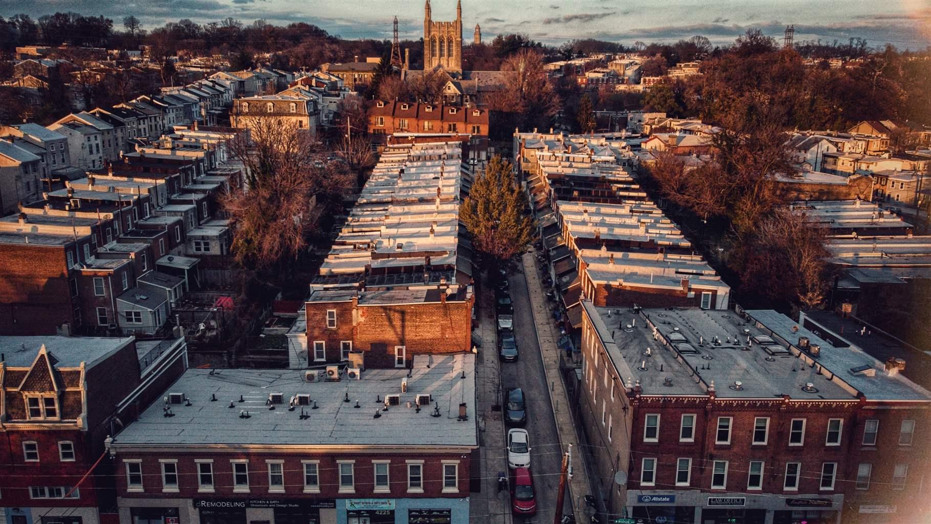 An aerial shot of a neighborhood in Philadelphia with rows of town houses and a large church in the distance. 