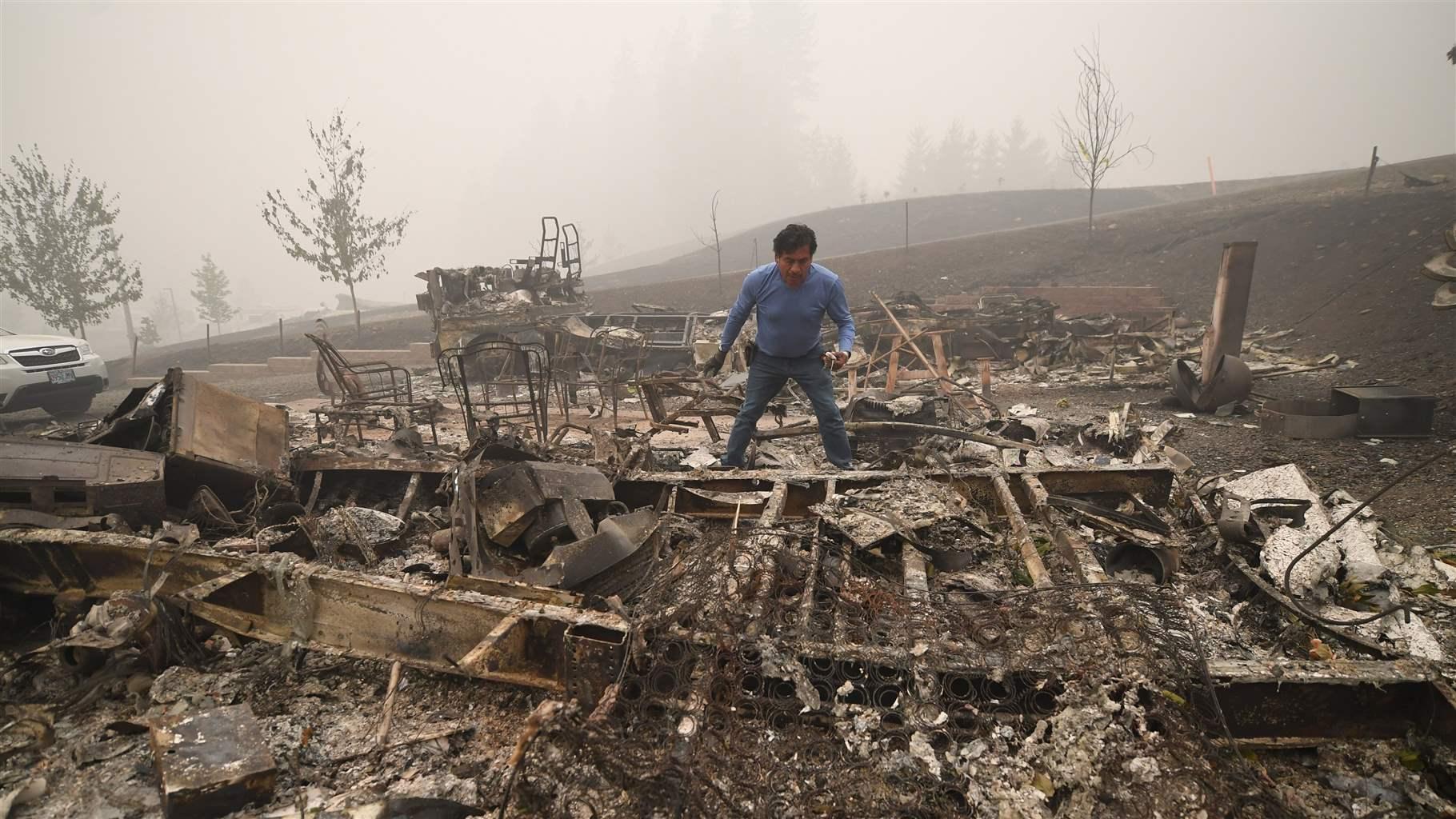 Marcelino Maceda looks for items in the remains of his mobile home after a wildfire sweep through the R.V. park destroying multiple homes in Estacada, Oregon September 12, 2020. - US officials girded today for the possibility of mass fatalities from raging wildfires up and down the West Coast, as evacuees recounted the pain of leaving everything behind in the face of fast-moving flames. Dense smog from US wildfires that have burnt nearly five million acres and killed 27 people smothered the West Coast on September 12. 