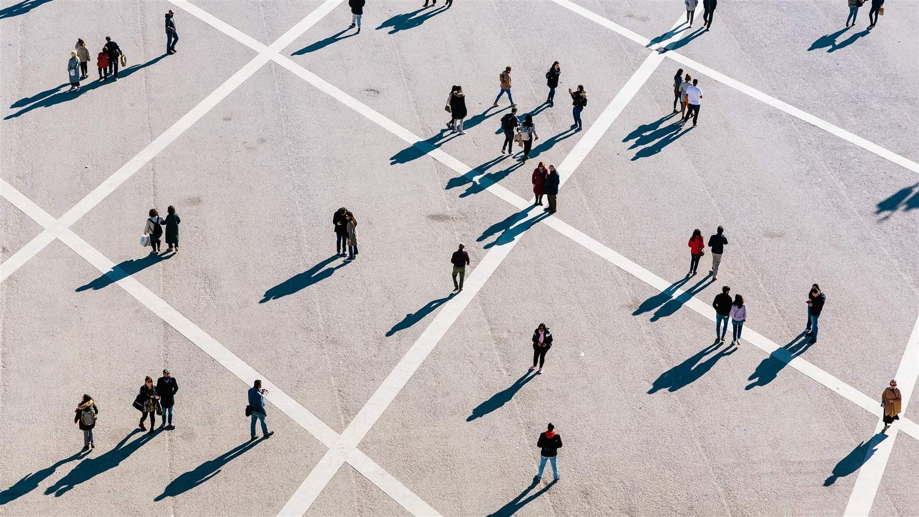 An aerial photo of people walking in a large open gridded space. 