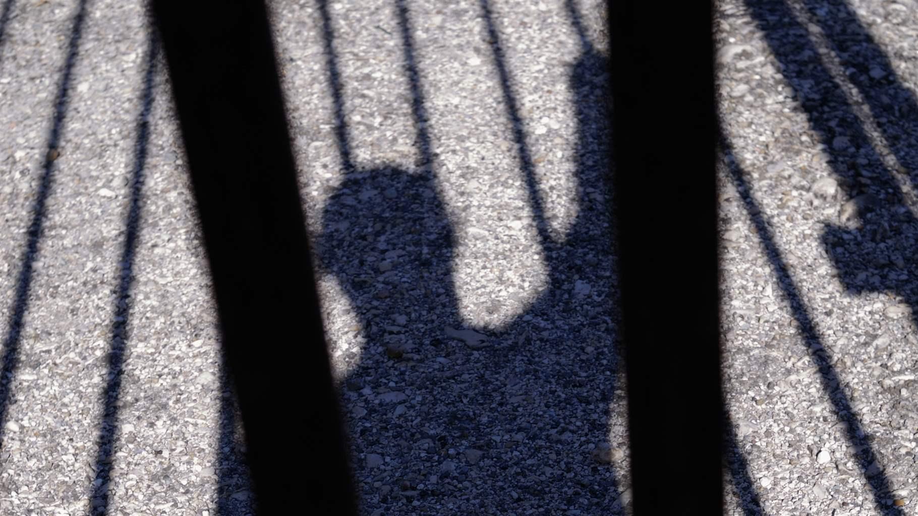 Silhouette of person behind bars