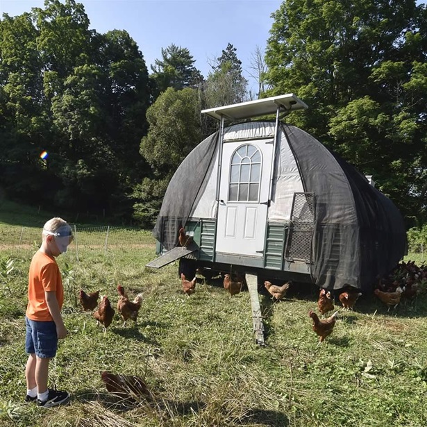 Landon wearing a face shield talks to the chickens outside of one of the chicken huts. Hillside Farms located in Shavertown, PA offers farm-based grief camps to children who have experienced trauma, loss through accident, illness, murder or suicide. 