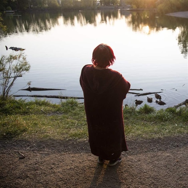 A woman who asked to remain anonymous stands outside her tent, looking over Bozeman Pond, at sunset in Bozeman, Mont., on Sept. 13, 2021. 
