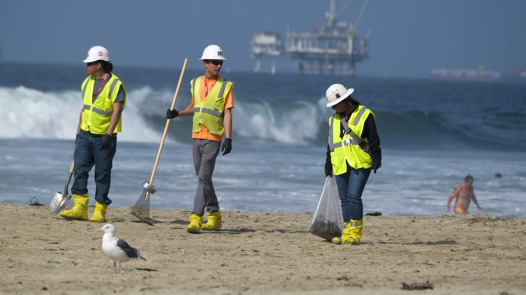 Workers in protective suits continue to clean the contaminated beach in Huntington Beach, Calif., Monday, Oct. 11, 2021. 