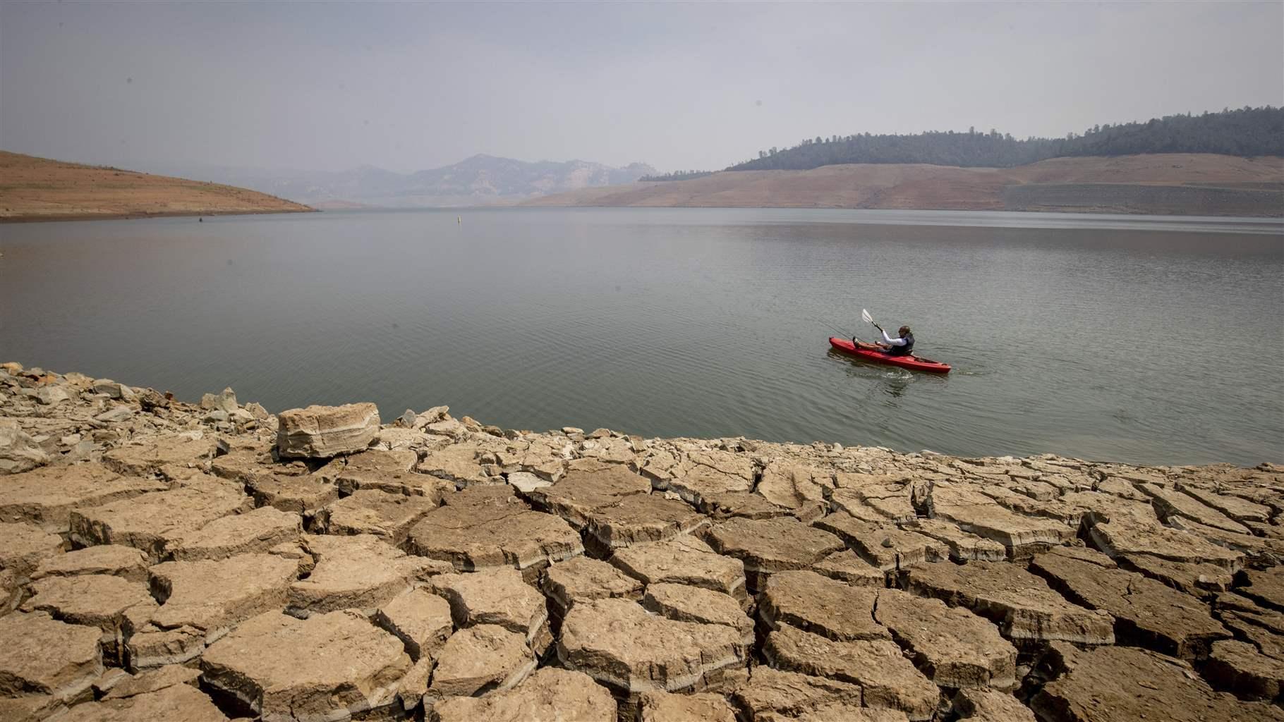  In this Aug. 22, 2021, file photo, a kayaker paddles in Lake Oroville as water levels remain low due to continuing drought conditions in Oroville, Calif.