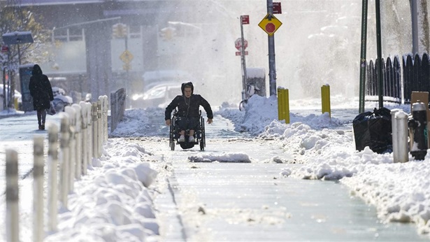 A person on a wheelchair uses the bike lane to navigate the snow covered streets in lower Manhattan, Friday, Jan. 7, 2022, in New York. 