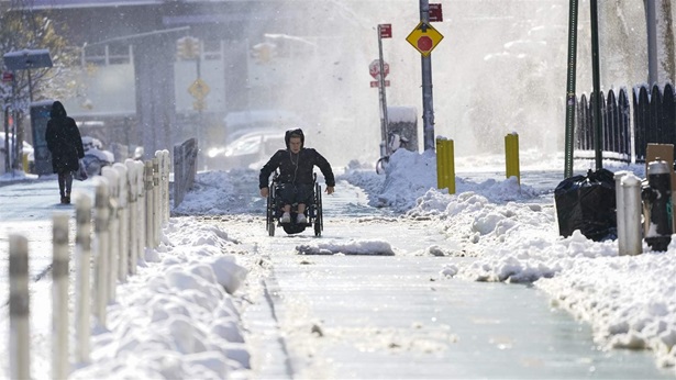 A person on a wheelchair uses the bike lane to navigate the snow covered streets in lower Manhattan, Friday, Jan. 7, 2022, in New York. A person on a wheelchair uses the bike lane to navigate the snow covered streets in lower Manhattan, Friday, Jan. 7, 2022, in New York.