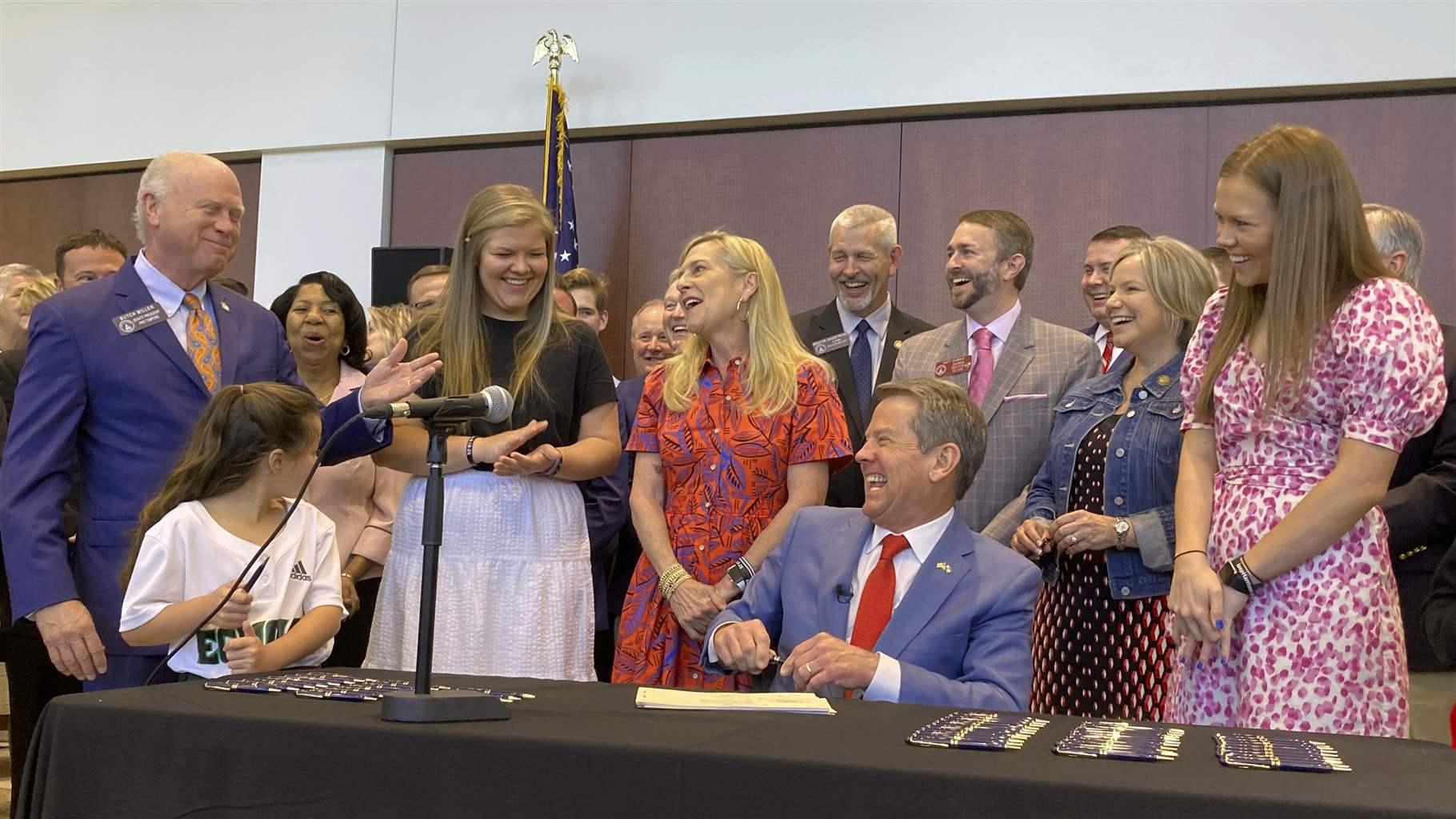Georgia Gov. Brian Kemp laughs with state Senate President Pro Tem Butch Miller and others as he signs education bills on Thursday, April 28, 2022 in Cumming, Ga. 