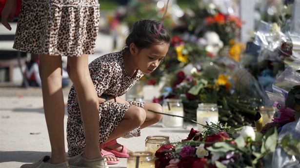 A child looks at a memorial site for the victims killed in this week's shooting at Robb Elementary School in Uvalde, Texas, Friday, May 27, 2022.