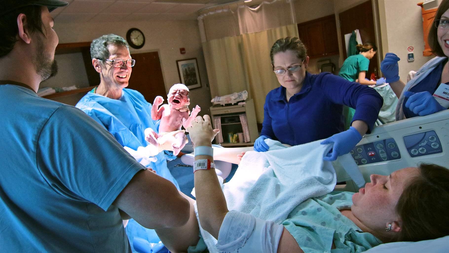 In this May 20, 2016 photo, Dr. Henry Hearn IV holds newborn Devin Hendrix Mann after delivery as Aaron Mann, left, and Amy Mann, right, look on at the AnMed Health Women and Children's Center in Anderson, S.C. Hearn is a second-generation doctor in Anderson. 