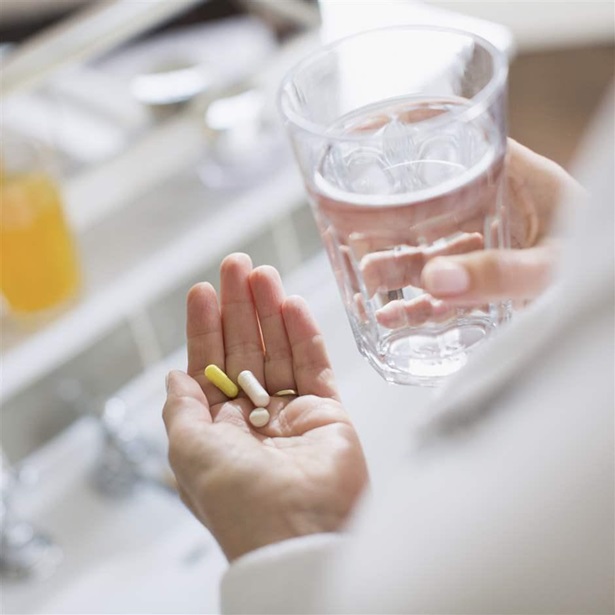 Woman taking supplements/vitamins and a glass of water