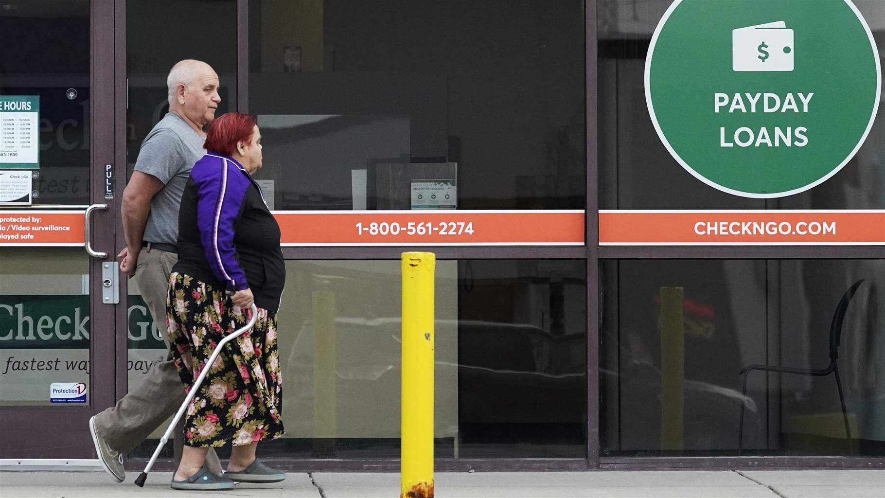 Couple walking by payday loans business