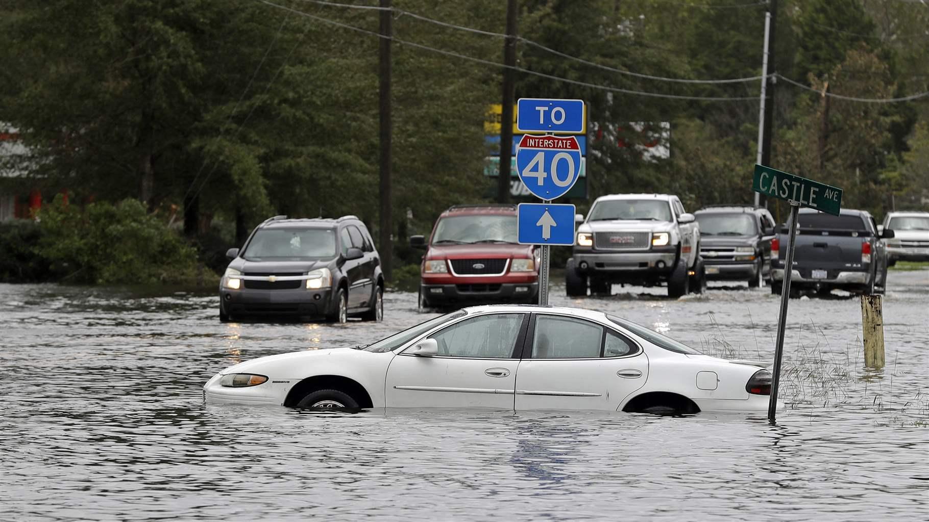 Cars try to navigate a flooded road 