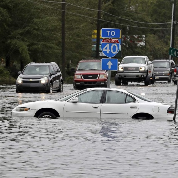 Cars try to navigate a flooded road 