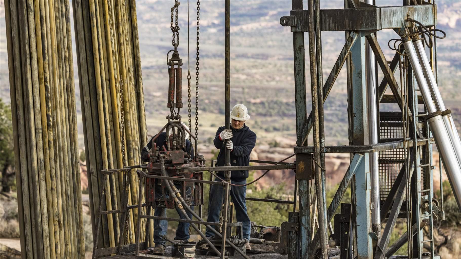 The well service crew on a workover rig uses power tongs to reconnect the sections of tubing on an oil well.