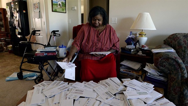 Debra Smith, 57, sorts through her medical bills in her living room on Thursday, Oct. 7, 2021, in Spring Hill, Tenn. Smith, who has health problems that prevent her from working, has about $10,000 in unpaid medical bills.