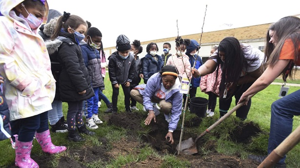 From center, family liaison coordinator LaTonia Mitchell, principal Dillondria Patterson and behavioral specialist Randi French show kindergarten students how to plant a pear tree as part of Earth Day activities in April at the Discovery Enrichment Center in Benton Harbor, Mich.