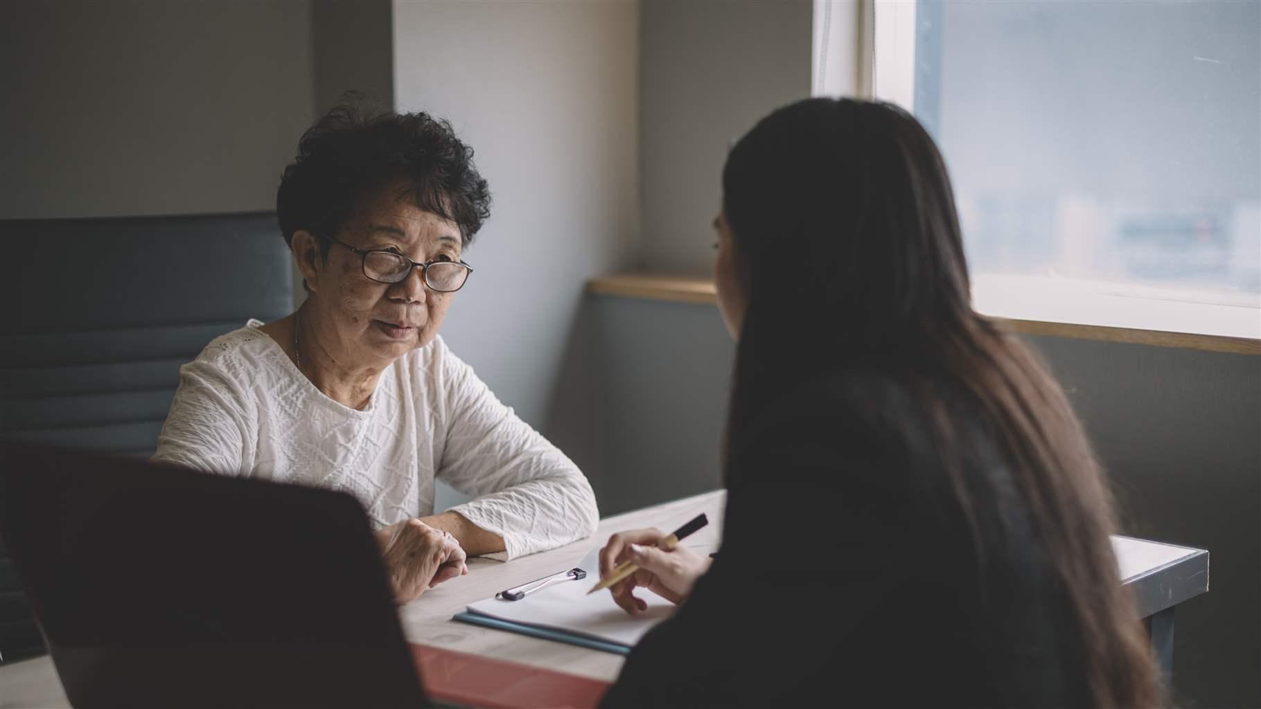 an asian chinese active senior woman having discussion with her chinese agent about her retirement investment plan