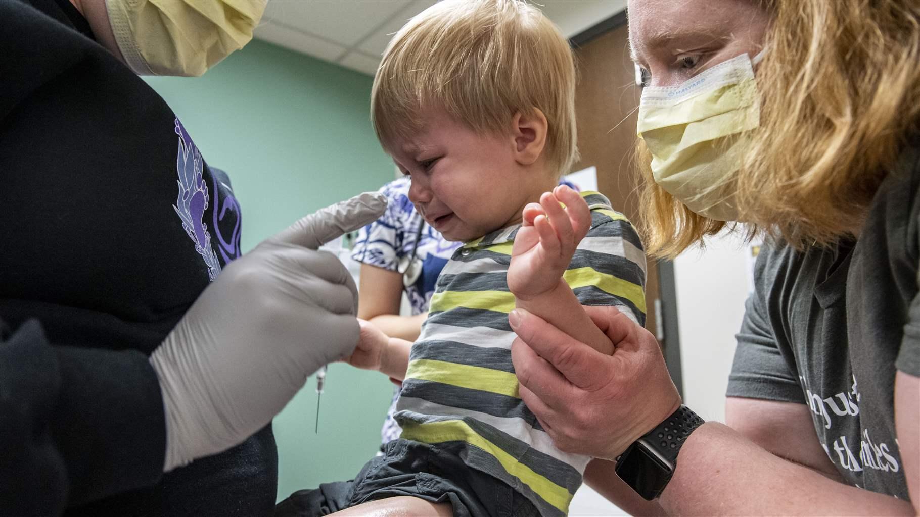 Pediatrician Dr. Joyce Remus, right, comforts her son Bryce, 20 months, as he receives his first dose of COVID-19 vaccine at the Mercy Pediatric Clinic in Cedar Rapids, Iowa, in June. The rate of children without health insurance declined during the pandemic. 