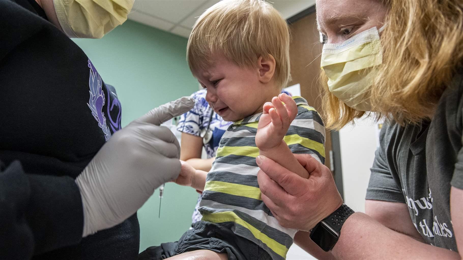 Pediatrician Dr. Joyce Remus, right, comforts her son Bryce, 20 months, as he receives his first dose of COVID-19 vaccine at the Mercy Pediatric Clinic in Cedar Rapids, Iowa, in June. The rate of children without health insurance declined during the pandemic. Pediatrician Dr. Joyce Remus, right, comforts her son Bryce, 20 months, as he receives his first dose of COVID-19 vaccine at the Mercy Pediatric Clinic in Cedar Rapids, Iowa, in June. The rate of children without health insurance declined during the pandemic.