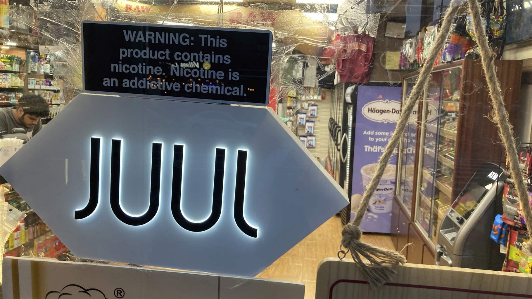 A Juul electronic cigarette sign hangs in the front window of a bodega convenience store in New York City on Saturday, June 25, 2022. 