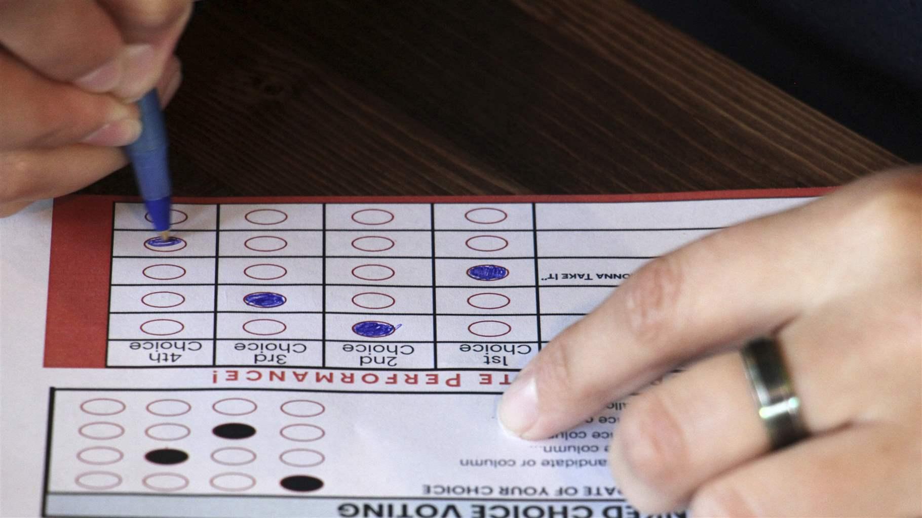 This July 28, 2022, photo shows a person completing a ballot in a mock election at Cafecito Bonito in Anchorage, Alaska, where people ranked the performances by drag performers. 