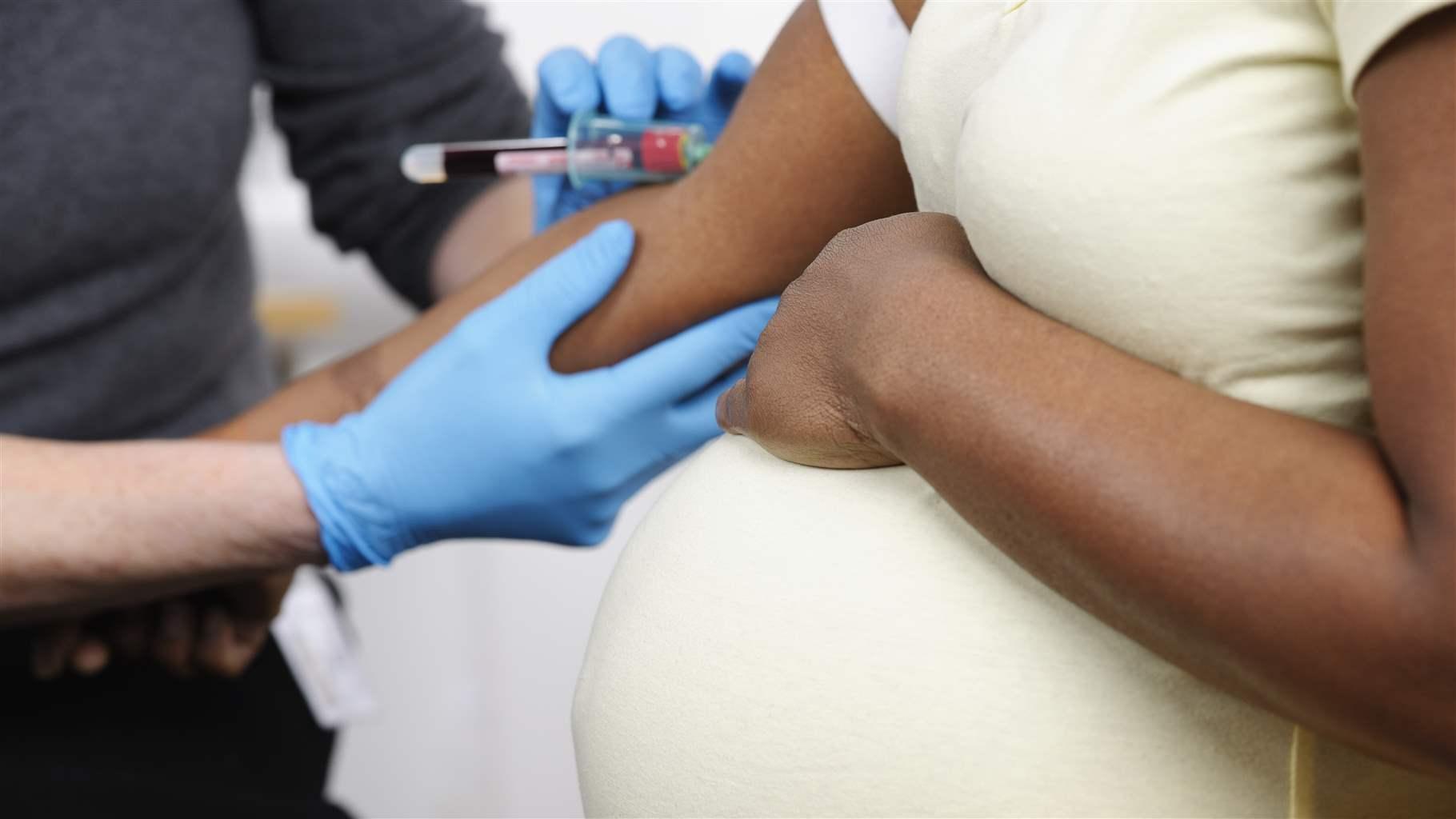 A close-up of a pregnant African American woman having bloods taken.