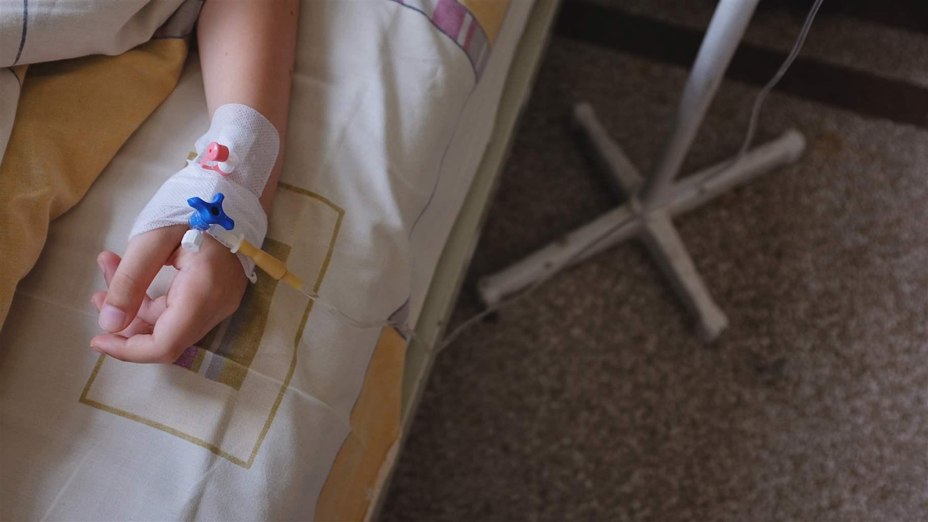 Child's hand in hospital bed, with IV drip attached