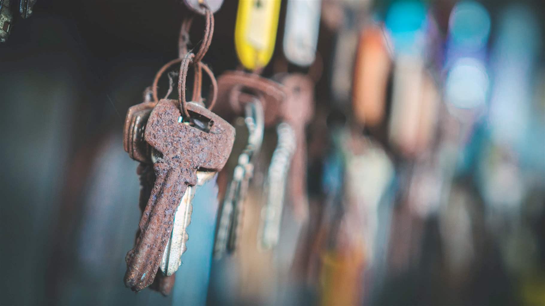 Close up of a rusted copper key in front of a teal background