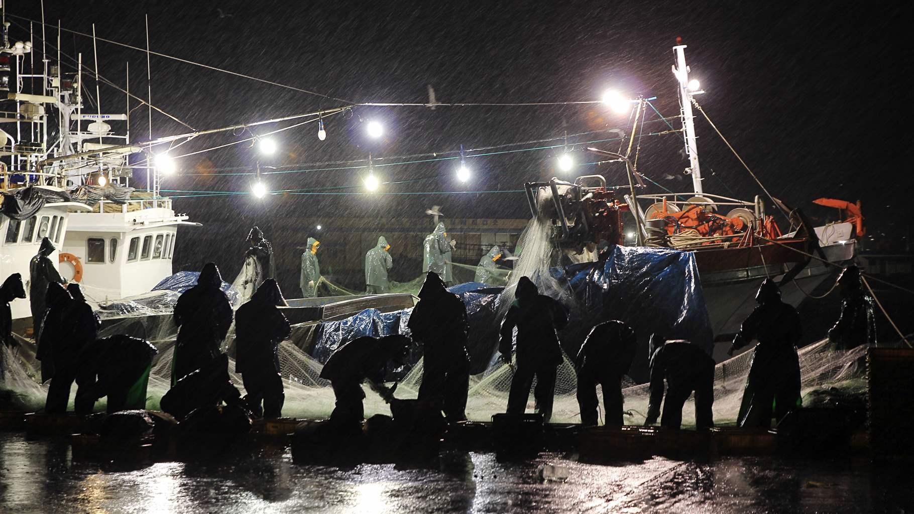 Fishermen Working Against Sky At Night During Monsoon