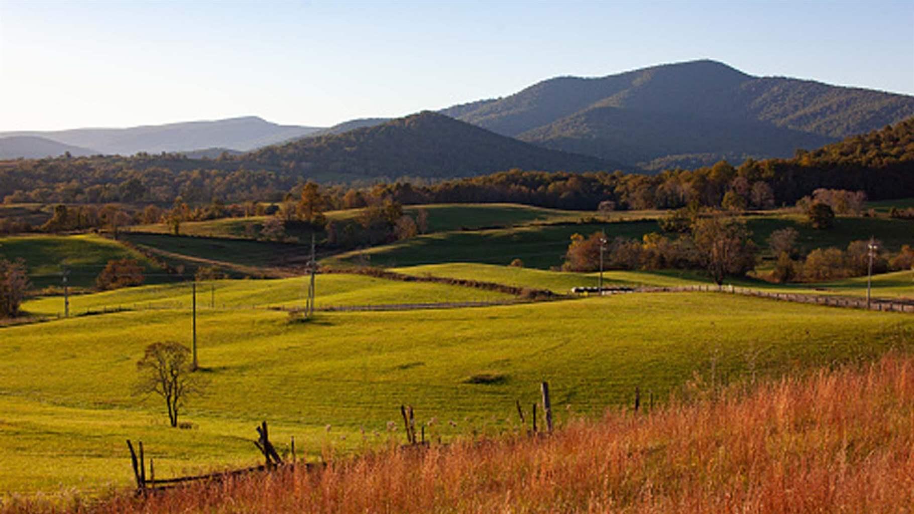 Landscape of rural Virginia with mountains in the background and hilly grass in the foreground